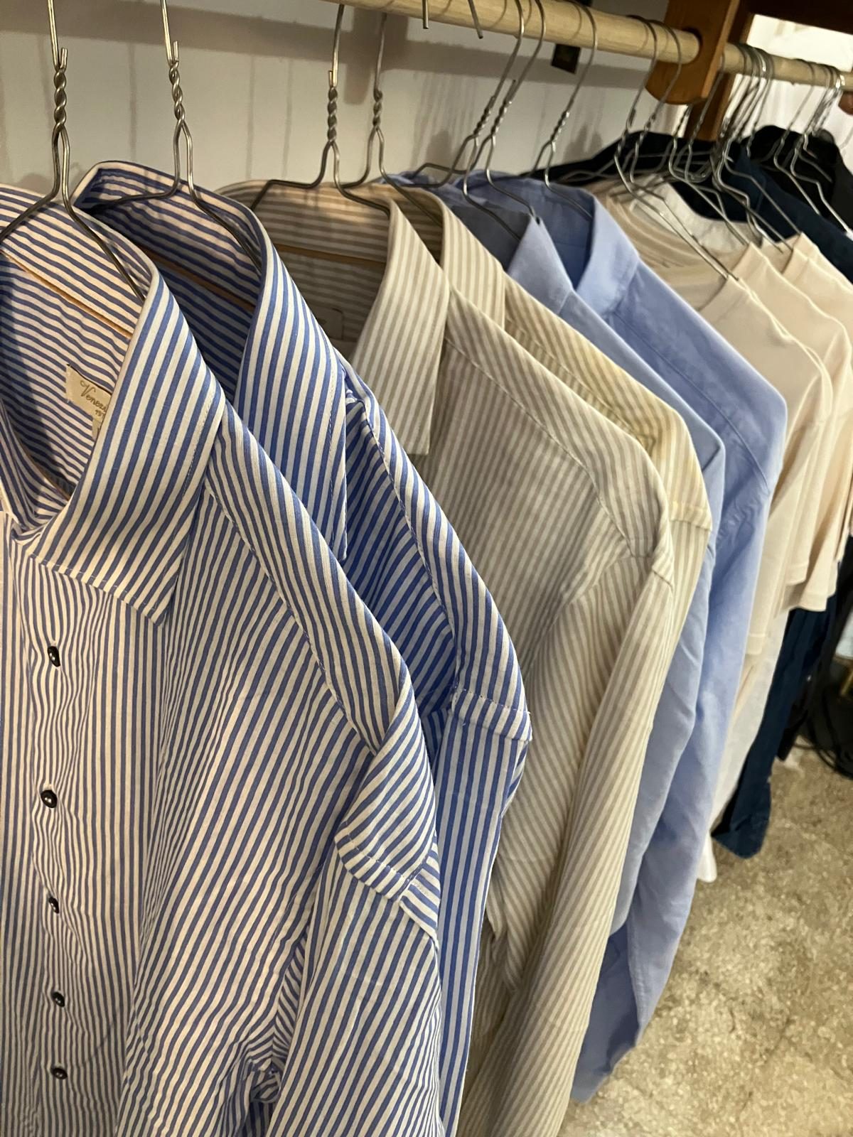 Camicie a righe blu e beige, azzurre e color crema appese su grucce metalliche nel negozio Lassassino Narni Vintage Store